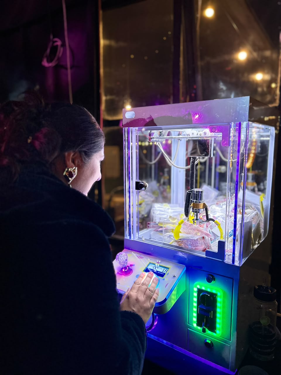 Una adulta jugando con la garra mecánica en un evento nocturno